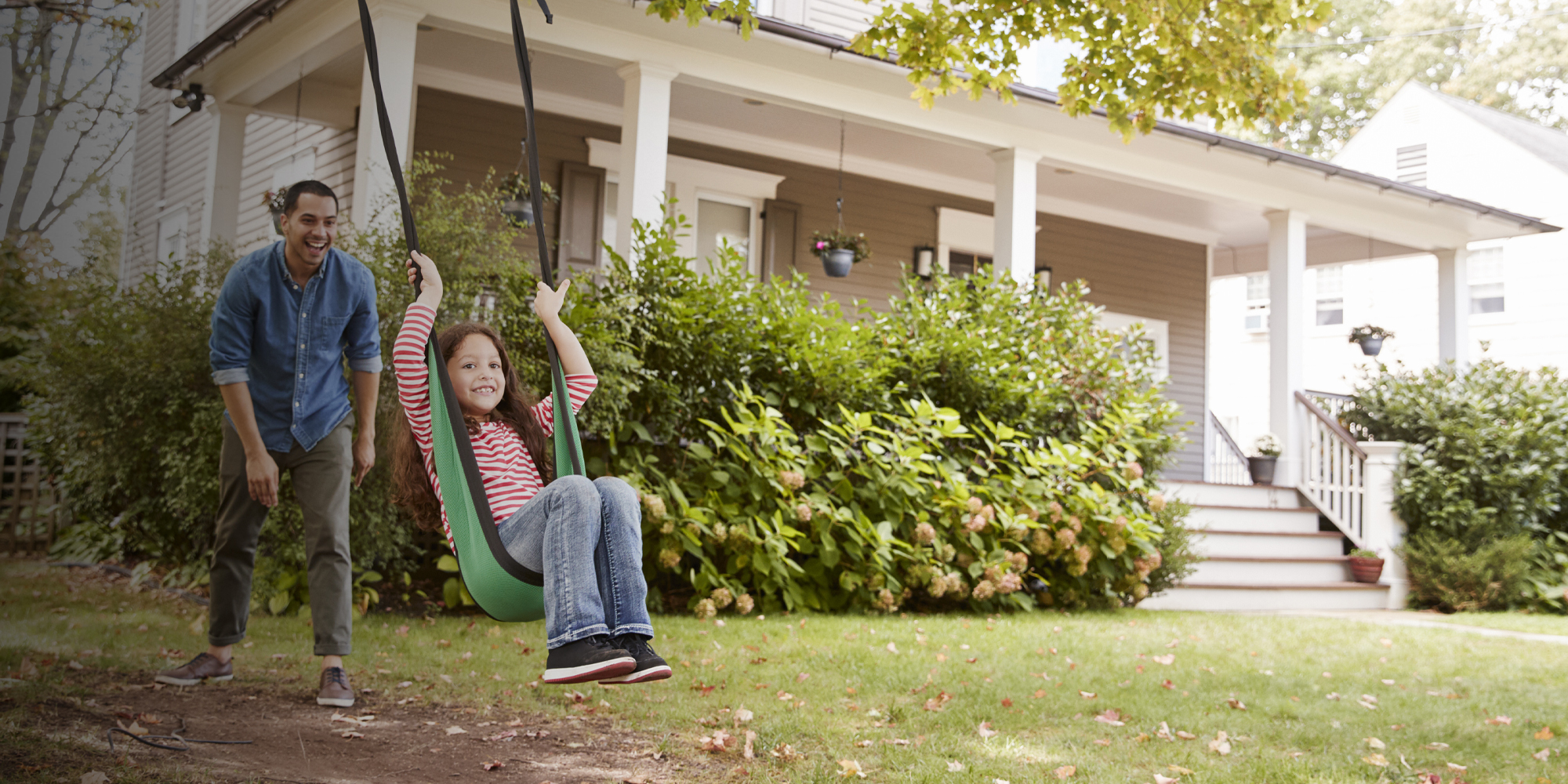 Young girl in a swing with father pushing her