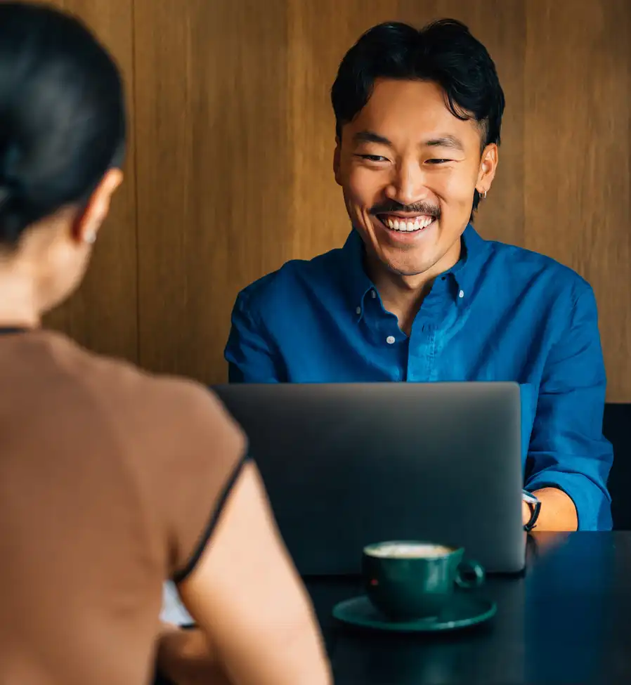man smiling at woman in cafe with laptop