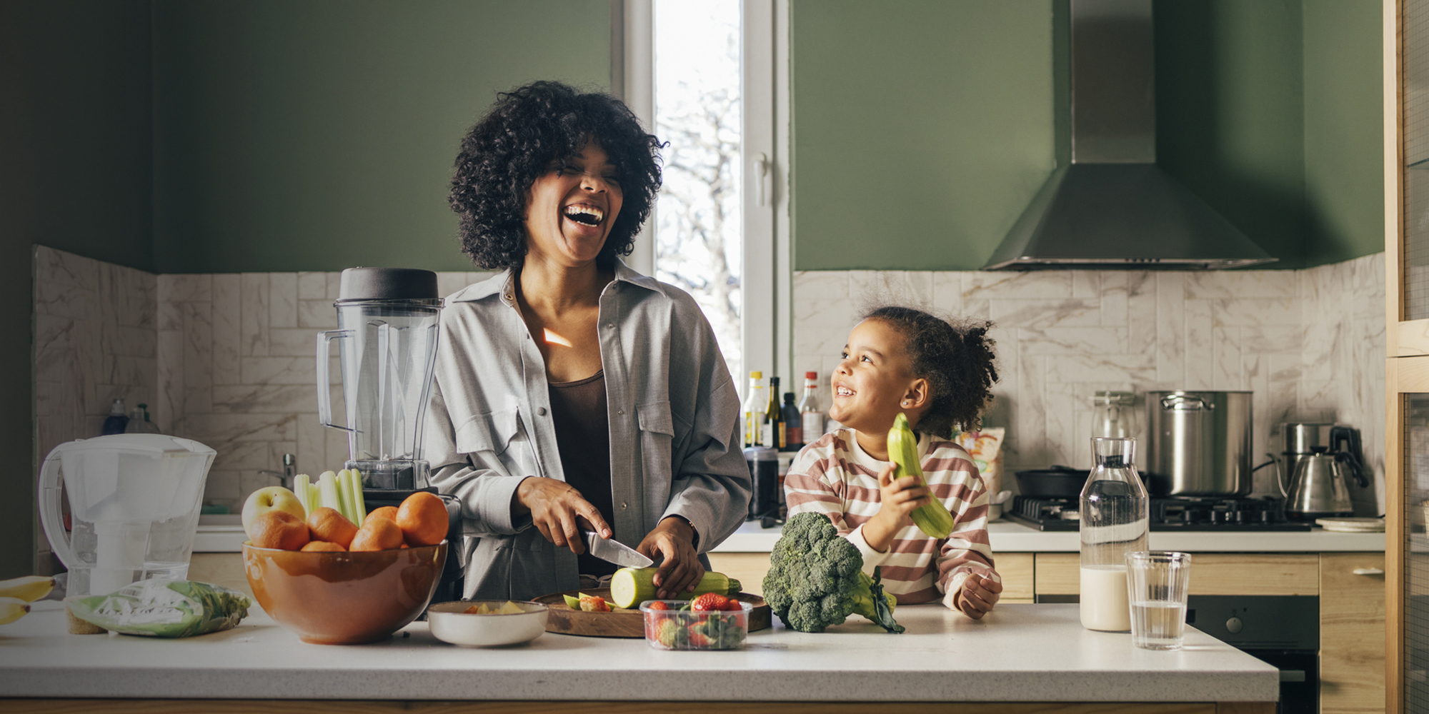 mom and daughter with fruit laughing in kitchen